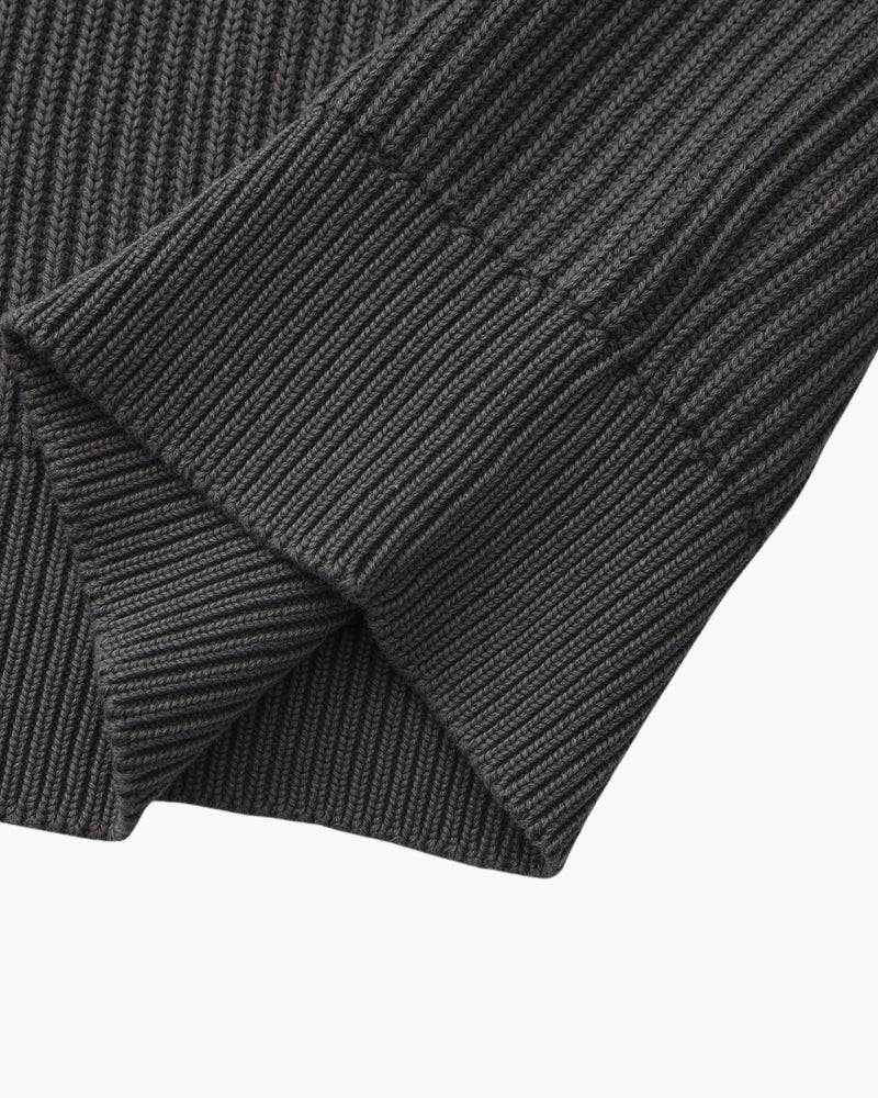 Close-up of charcoal-grey rib-knit jumper sleeve folded to show the ribbed cuff and chunky rib texture