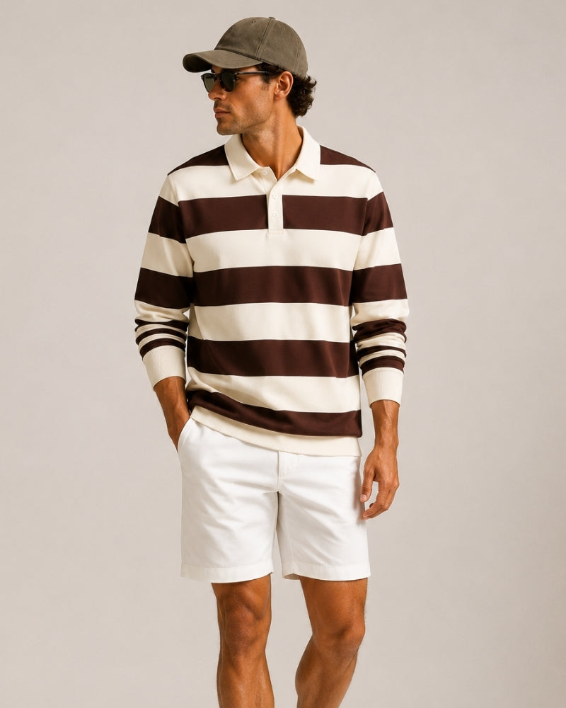 Hombre con polo de rugby a rayas marrón y crudo y shorts blancos, mano en el bolsillo, vista de tres cuartos