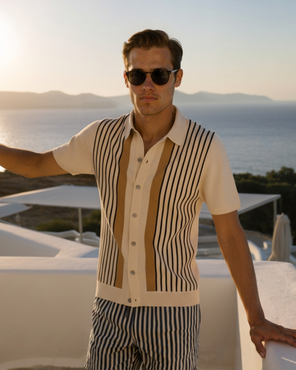 Cream knit polo with black vertical stripes and tan centre panel, worn on a seaside terrace