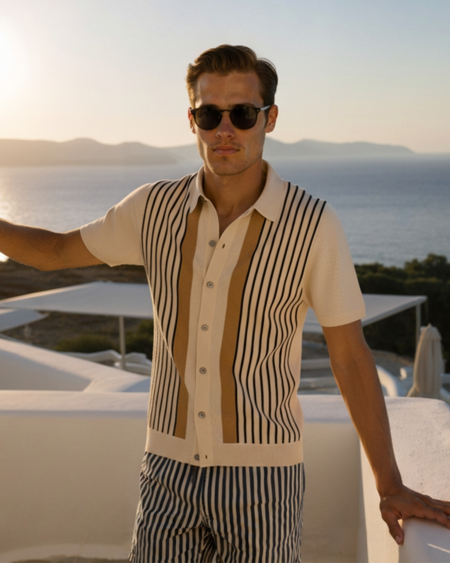 Cream knit polo with black vertical stripes and tan centre panel, worn on a seaside terrace