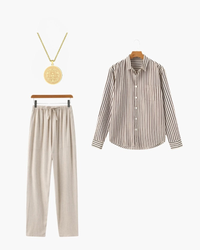 Brown and white striped shirt, beige trousers and gold medallion necklace, flat-lay set