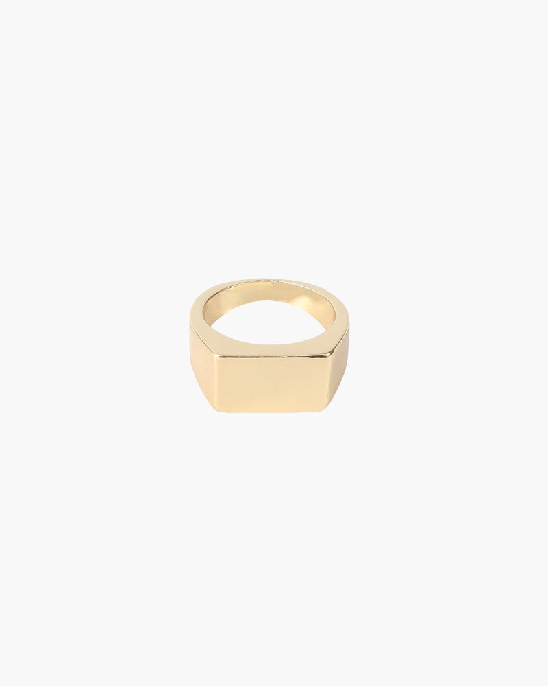 Anillo de sello rectangular dorado con superficie plana, vista frontal sobre blanco