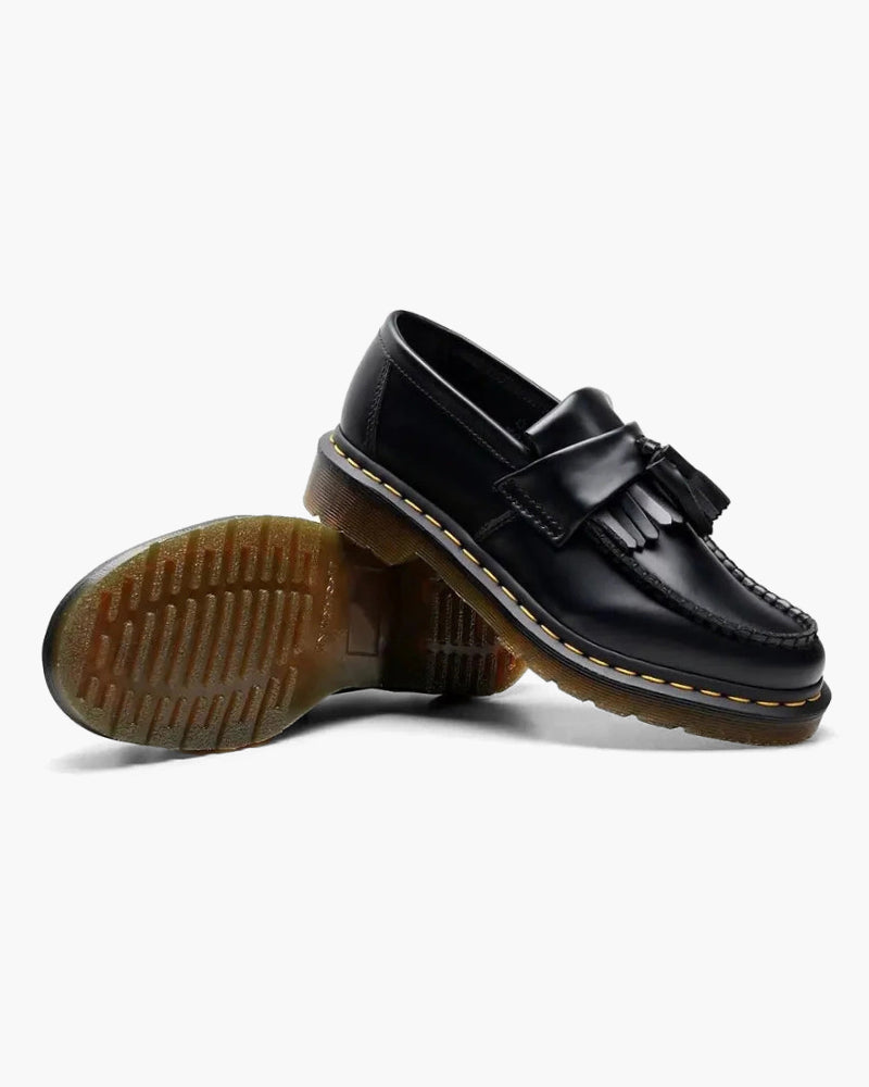 Black leather tassel loafer with the studded tan sole turned beside it