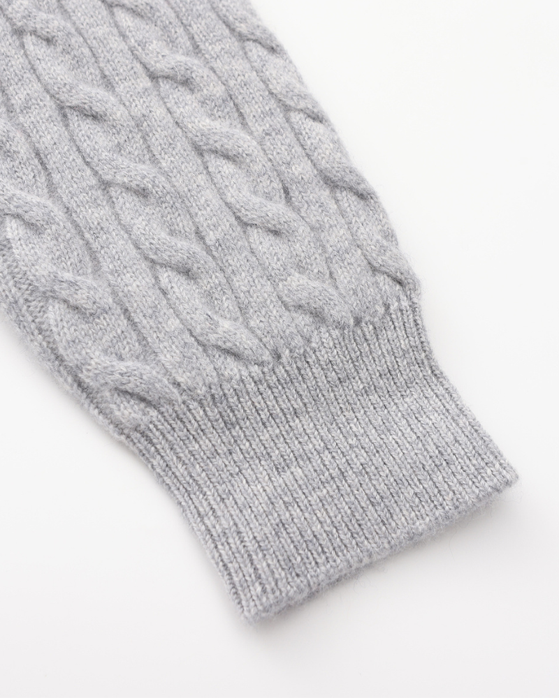 Close-up of a grey cable-knit cashmere sleeve with ribbed cuff, flat on white