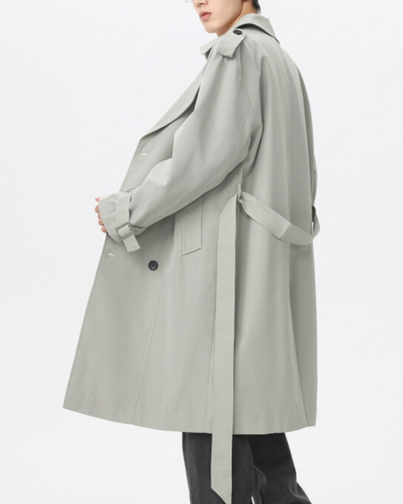 Side view of a sage grey-green trench coat worn open with belt hanging, on model